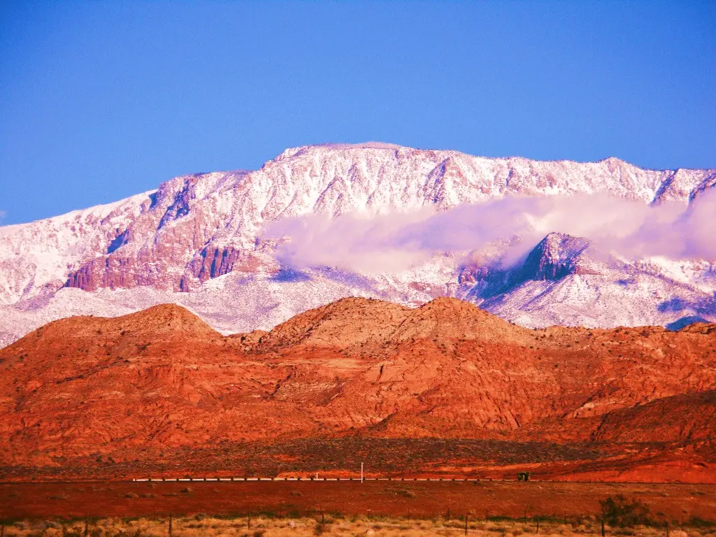 Snow-capped Pine Valley Mountain rising above red sandstone cliffs and high desert in southwestern Utah