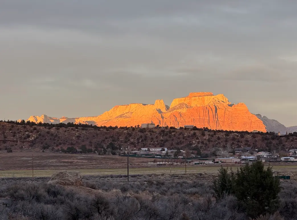 A long sandstone mesa lit orange by low sun above the valley near Apple Valley, Utah